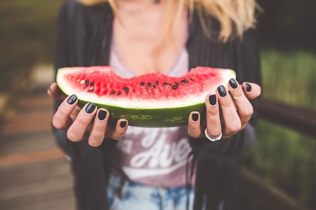 Outdoor Summer Fundraising: A girl holding a watermelon while at a crowdfunding event.